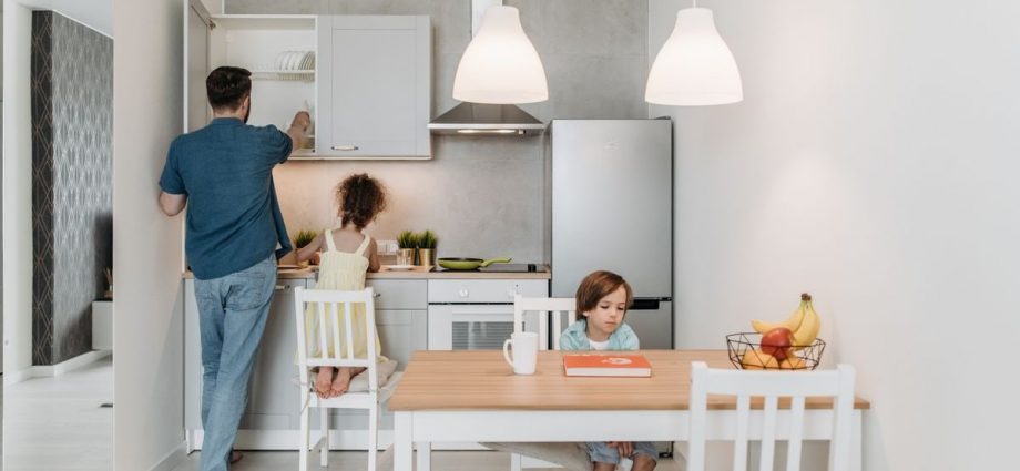 A father and children enjoying quality time in a bright, modern kitchen area.